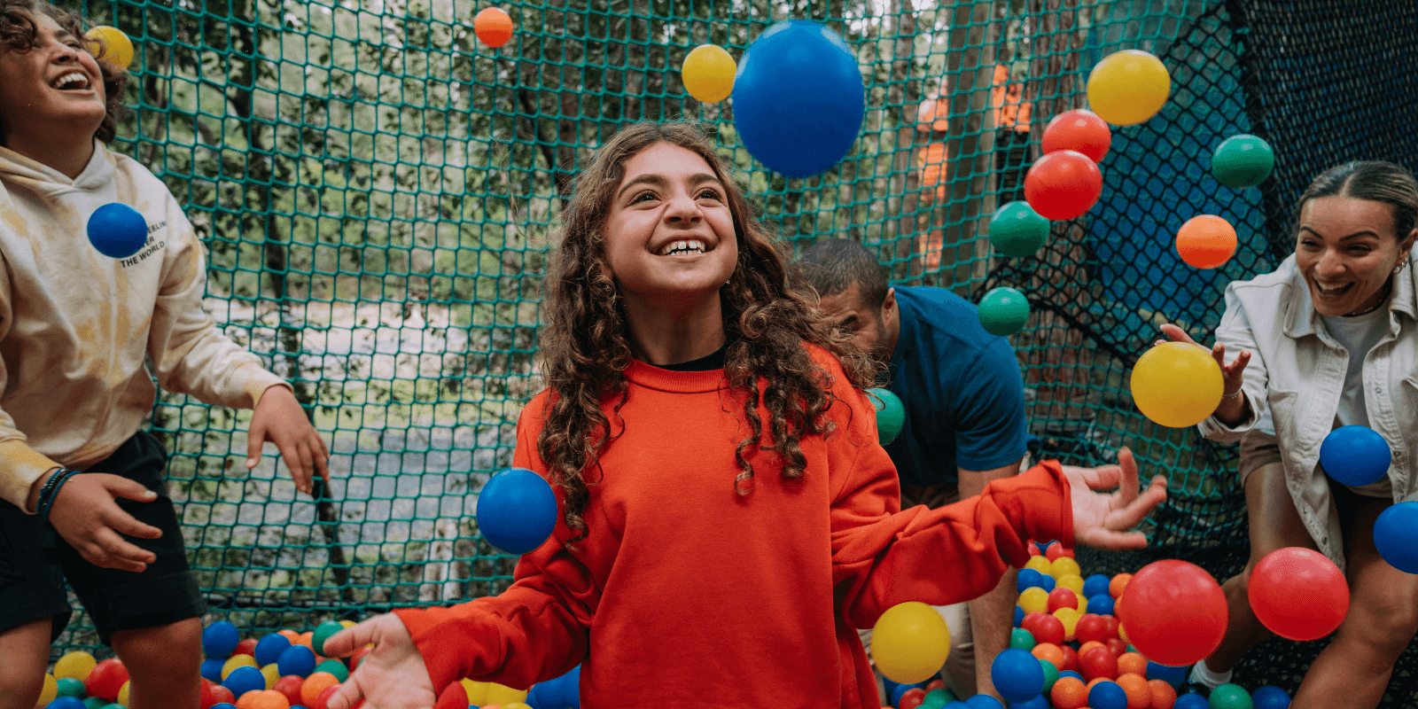 A child looking excited as they play in a colourful ball pit